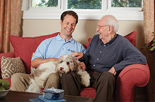 Younger man and senior petting a dog